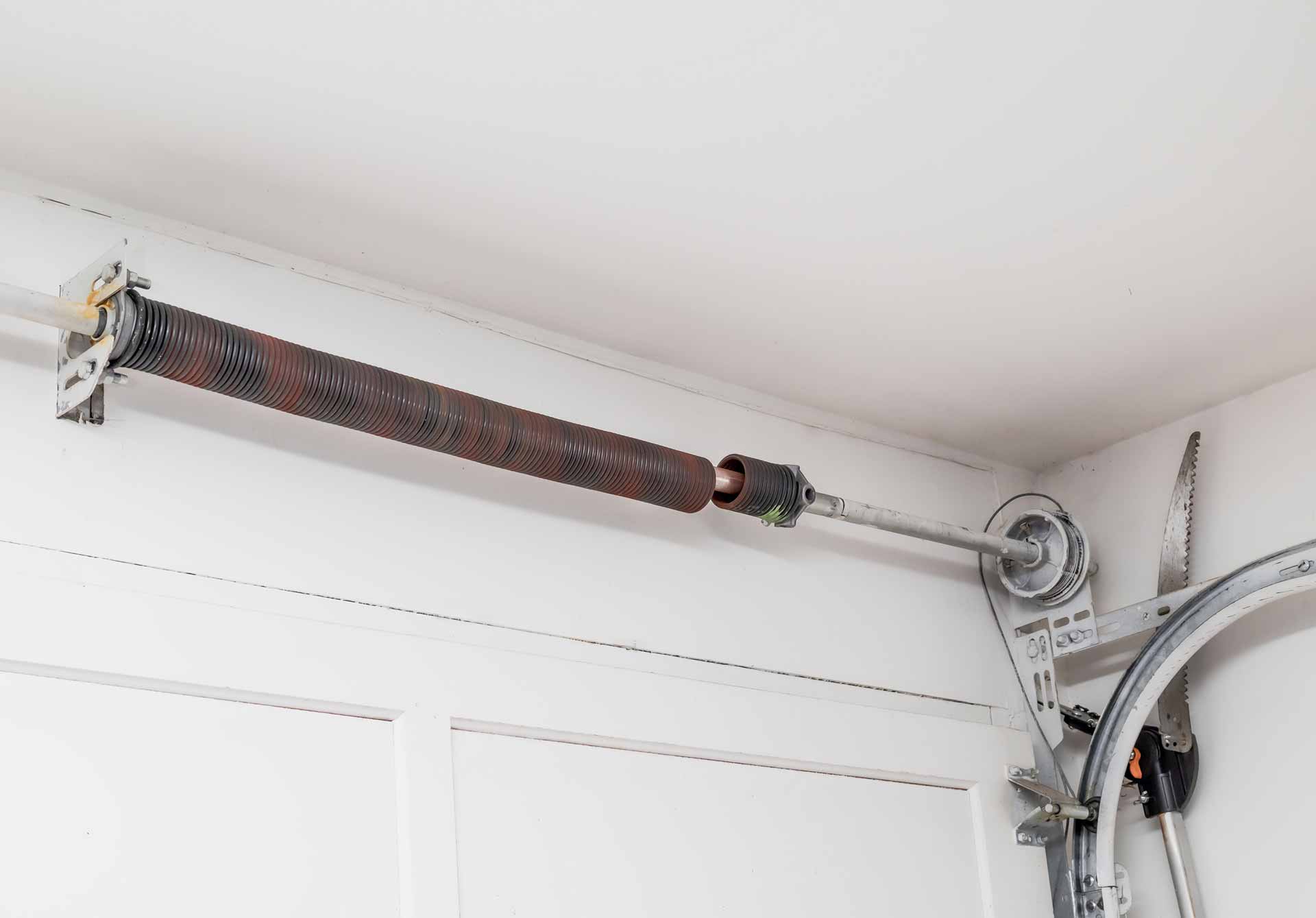 Broken garage door spring being inspected